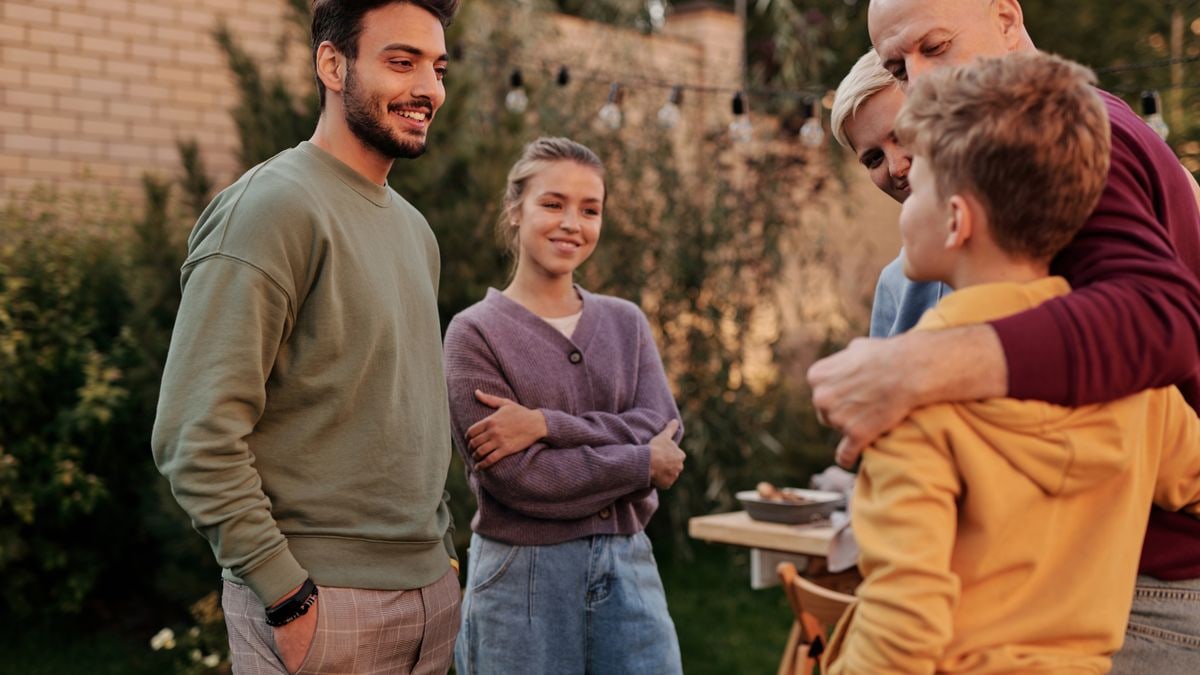 Group of cheerful multiracial relatives smiling and communicating in yard during meeting in summer weekends