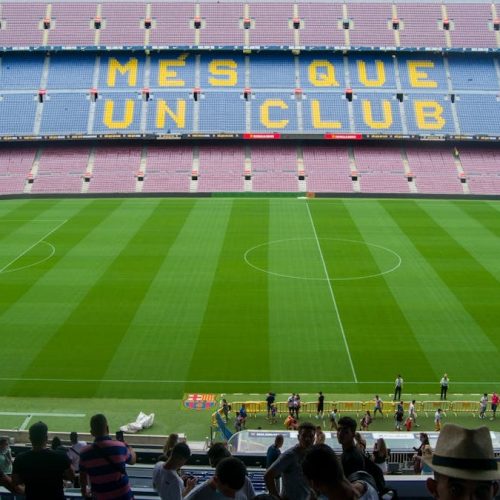 Aerial view of Camp Nou Stadium in Barcelona, showcasing the iconic 'Més Que Un Club' seating in daylight.