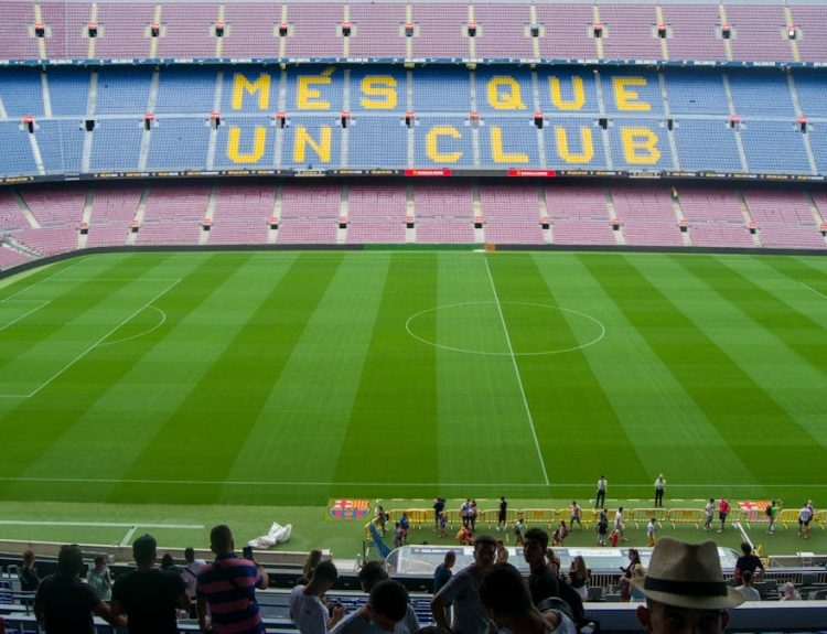 Aerial view of Camp Nou Stadium in Barcelona, showcasing the iconic 'Més Que Un Club' seating in daylight.
