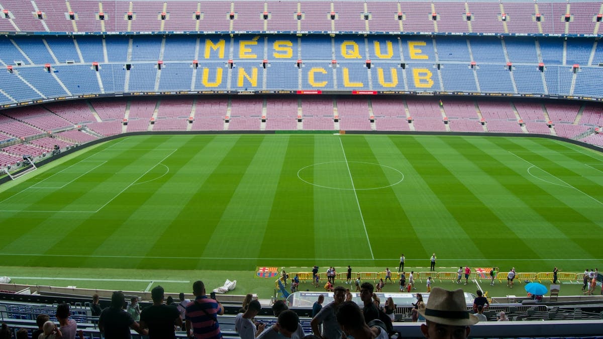 Aerial view of Camp Nou Stadium in Barcelona, showcasing the iconic 'Més Que Un Club' seating in daylight.